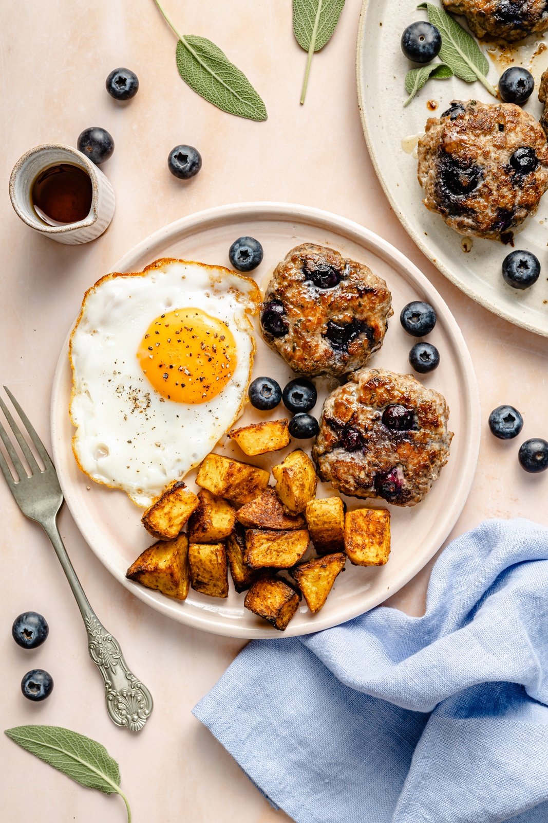 blueberry breakfast patties on a plate with a fried egg and potatoes