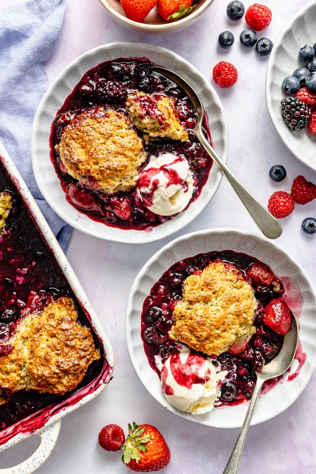 fresh berry cobbler in two bowls with ice cream