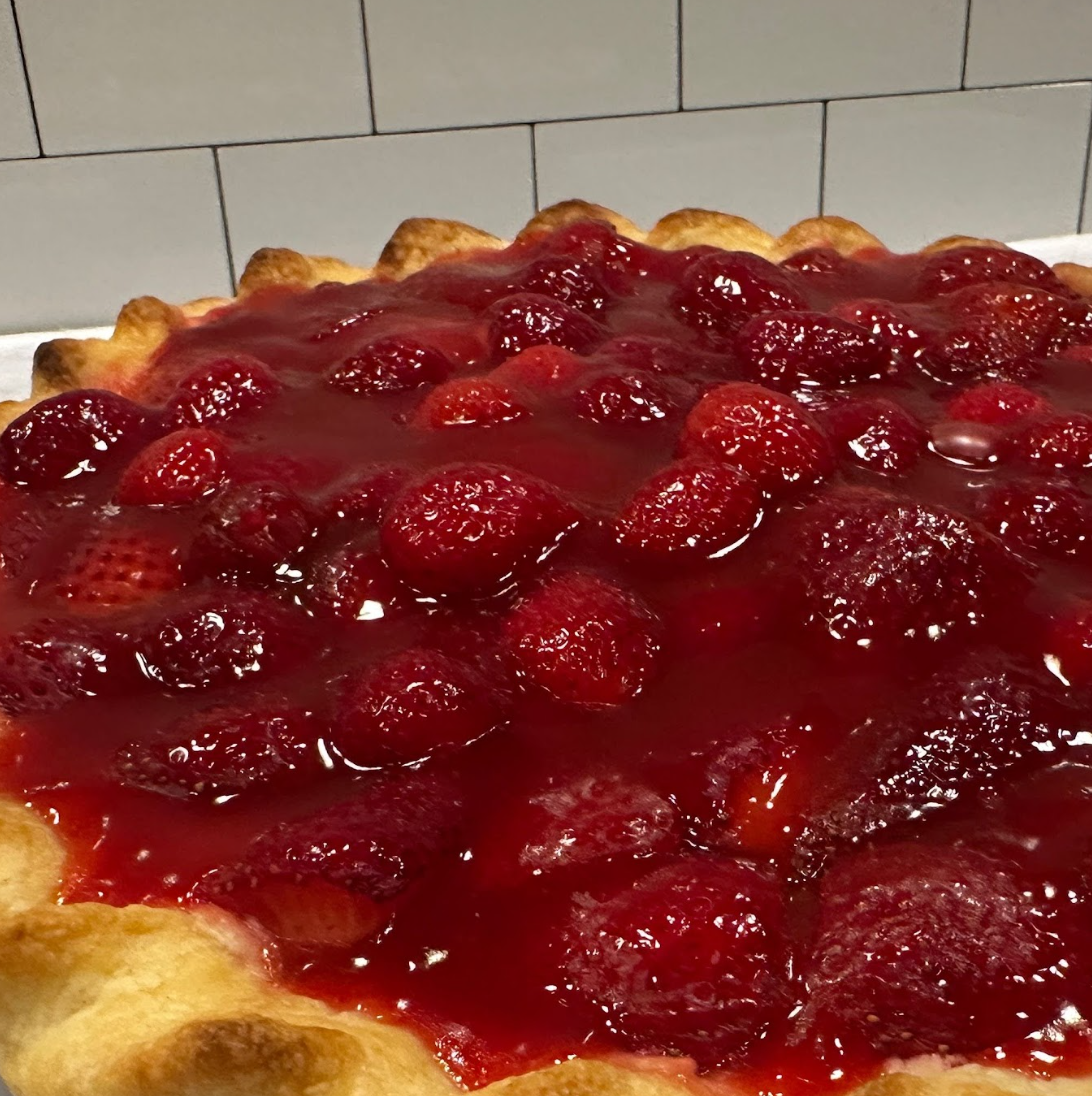 A fresh strawberry cream pie with a shiny glaze in a flaky pie crust. 