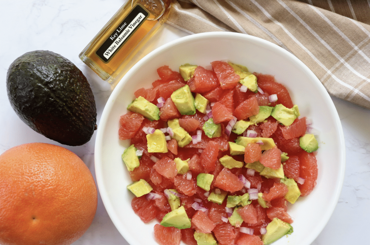 Citrus avocado salad in a bowl with a striped linen in the background.