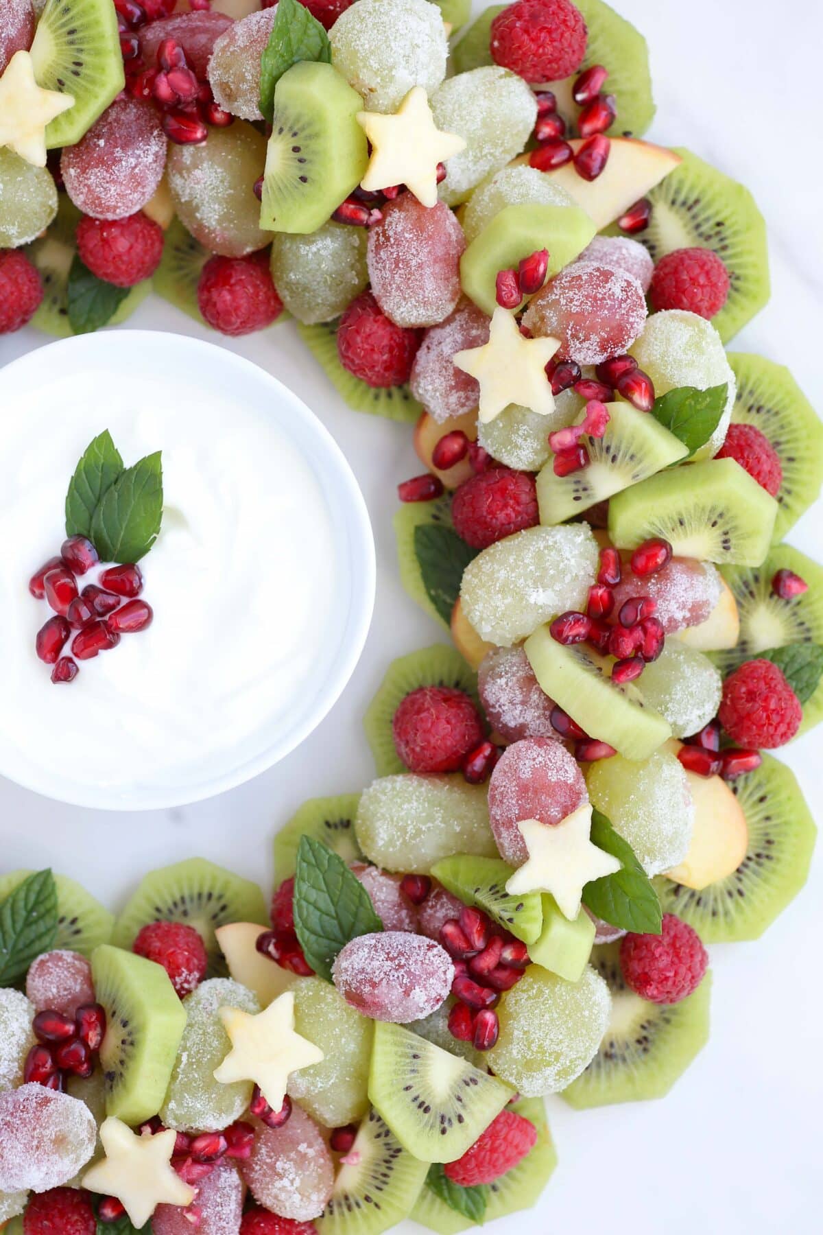 Kiwi, apples, pomegranate, and sugared grapes shaped into a wreath with fruit dip.