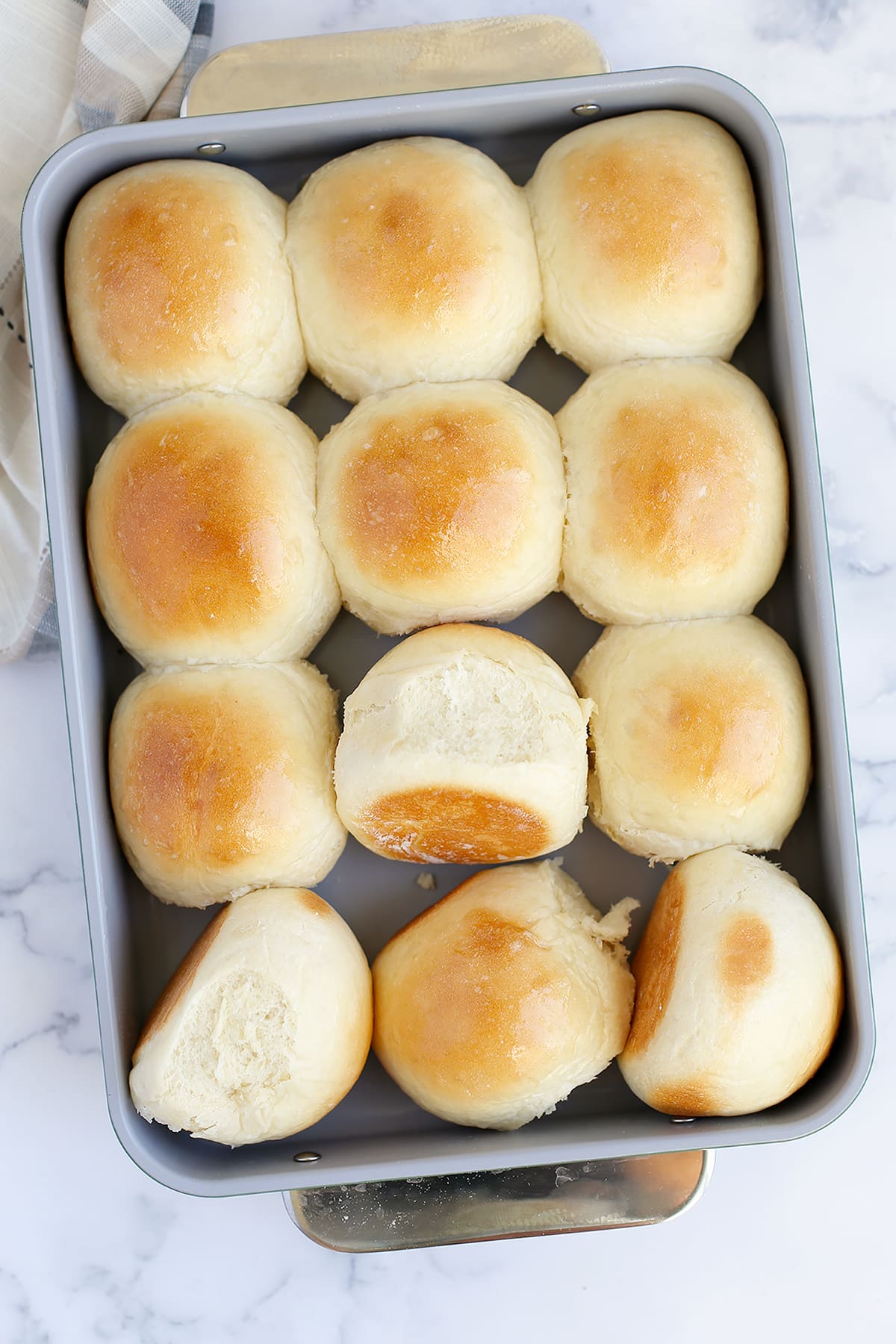Light and fluffy homemade rolls in a gray baking dish. 